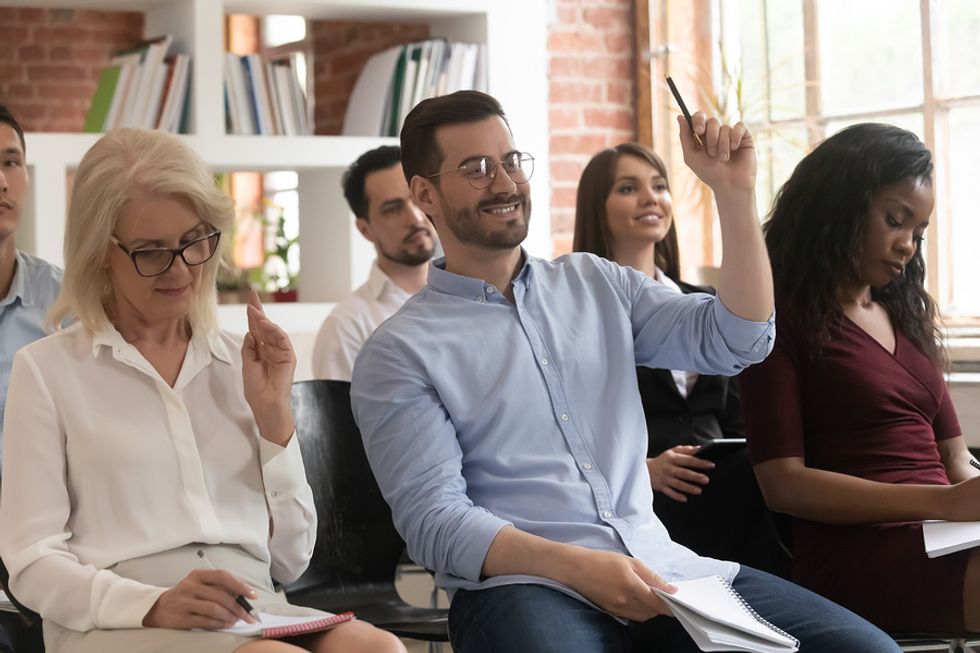 Jeune employé masculin posant joyeusement une question lors de sa première journée de travail.