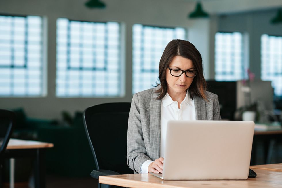 Femme d'affaires assise au bureau avec un ordinateur portable et se concentrant sur ses tâches les plus importantes au travail