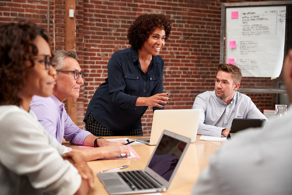 Une dirigeante heureuse prenant des initiatives et partageant les opportunités qu'elle voit au travail lors d'une réunion d'équipe