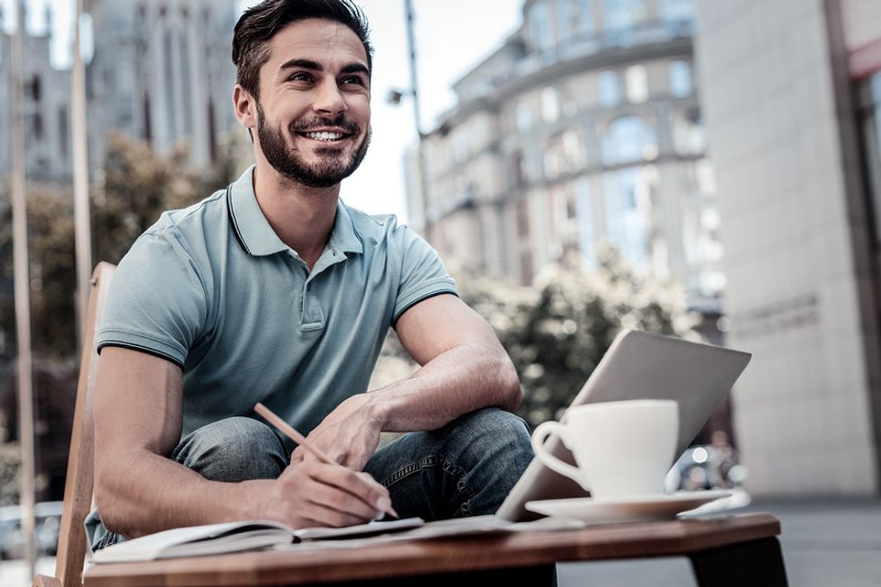 Un homme heureux qui écrit son idée d'entreprise et réfléchit à ses compétences en leadership