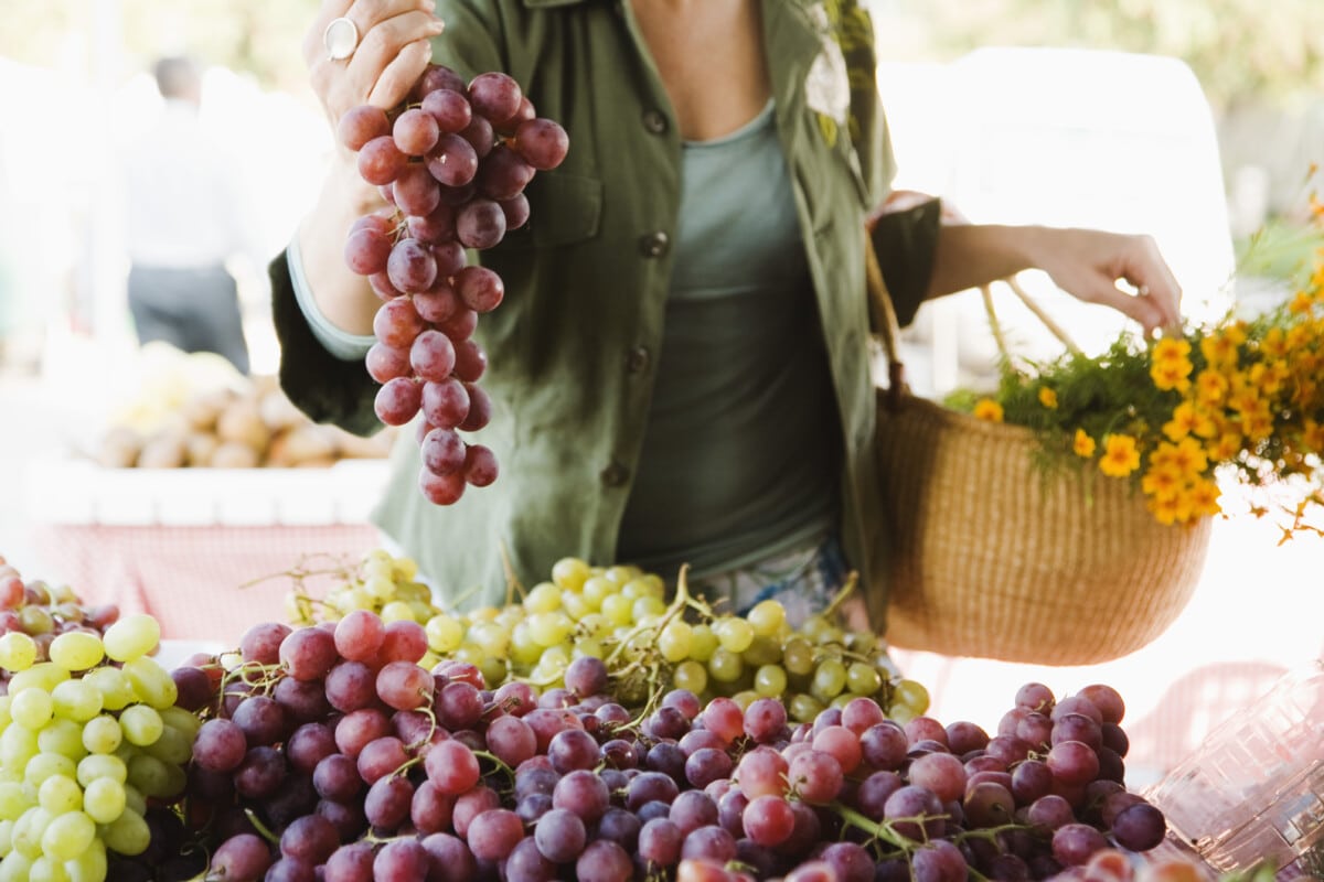 Femme avec des raisins au marché fermier