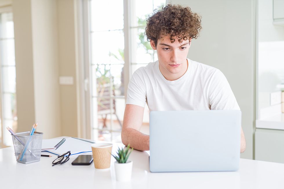 Jeune homme utilisant un ordinateur portable et optimisant correctement son profil LinkedIn afin d'obtenir plus de vues des employeurs